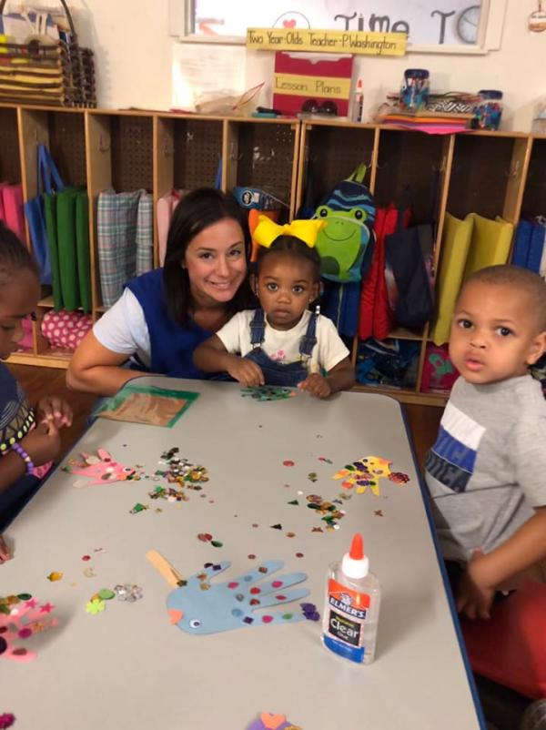 Junior Auxiliary of Greenwood member volunteering with schools and sitting at a table with two children. 