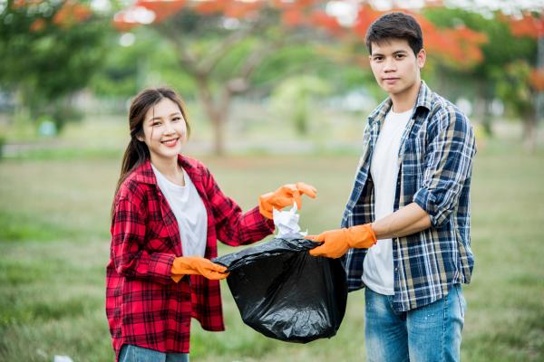 Photo of two students participating a park clean up community service event. Students can log verified service hours on their phone at any time!