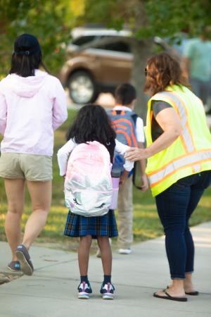 Parent holding arm of a child while volunteering for traffic duty