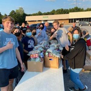 Group of Beta Club students at a community service event around a table of collected food